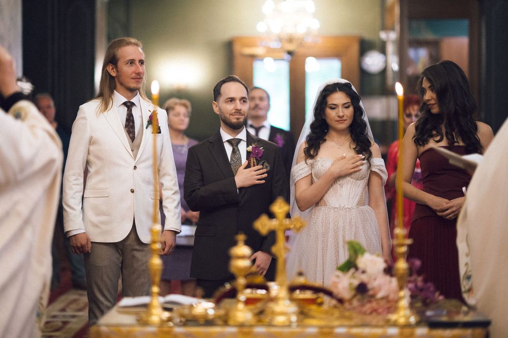 Couple exchanges vows at elegant Orthodox church wedding ceremony with guests and golden cross in foreground.