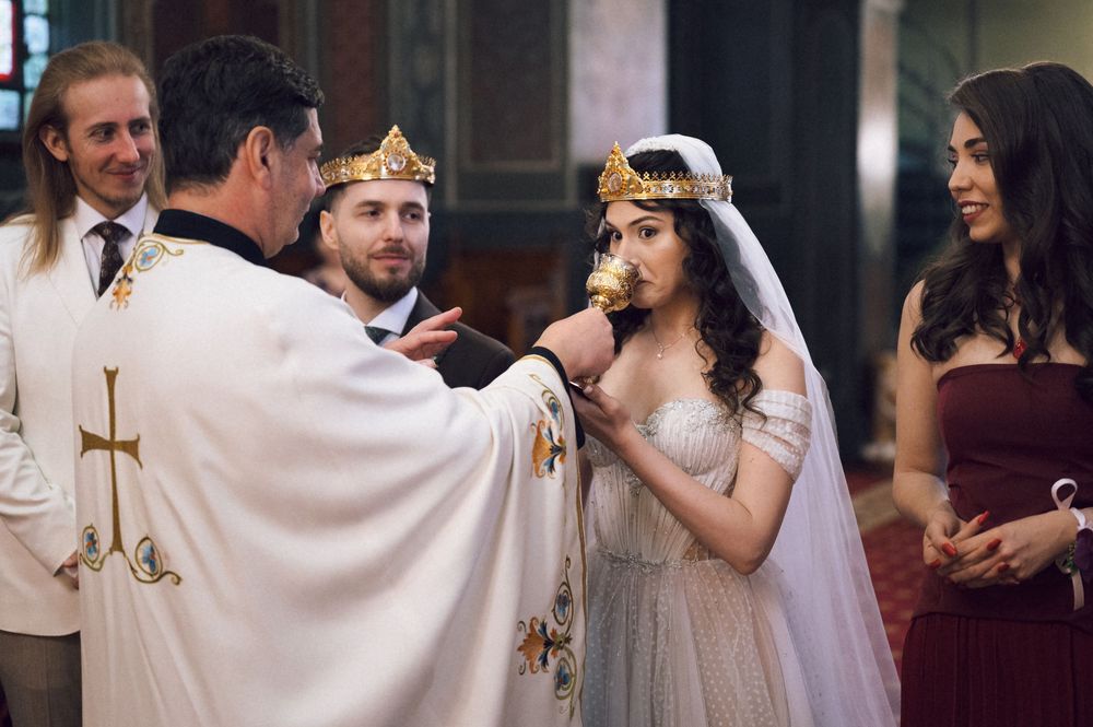 A bride and groom receive communion from a priest during a traditional wedding ceremony in a church.