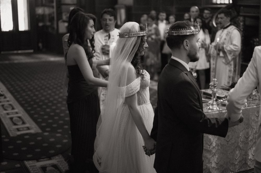 Black and white wedding ceremony photo of bride and groom exchanging vows in an elegant church.