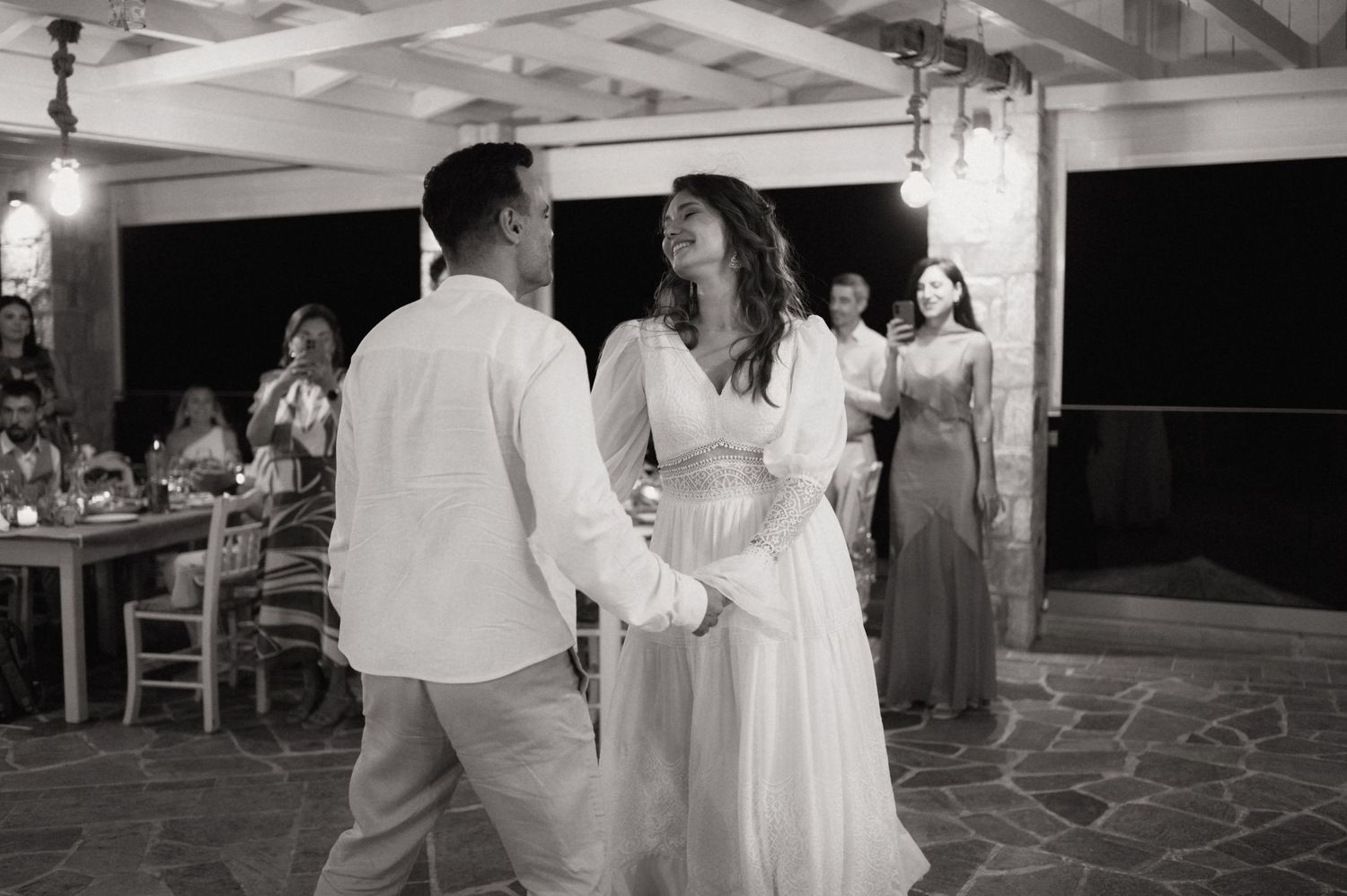 Black and white photo of a bride and groom sharing their first dance at an outdoor wedding reception.
