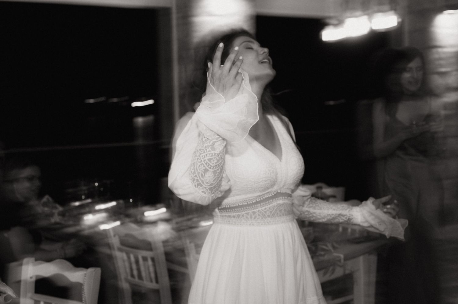 Bride in white lace gown dancing elegantly at a wedding reception in a black and white photo.