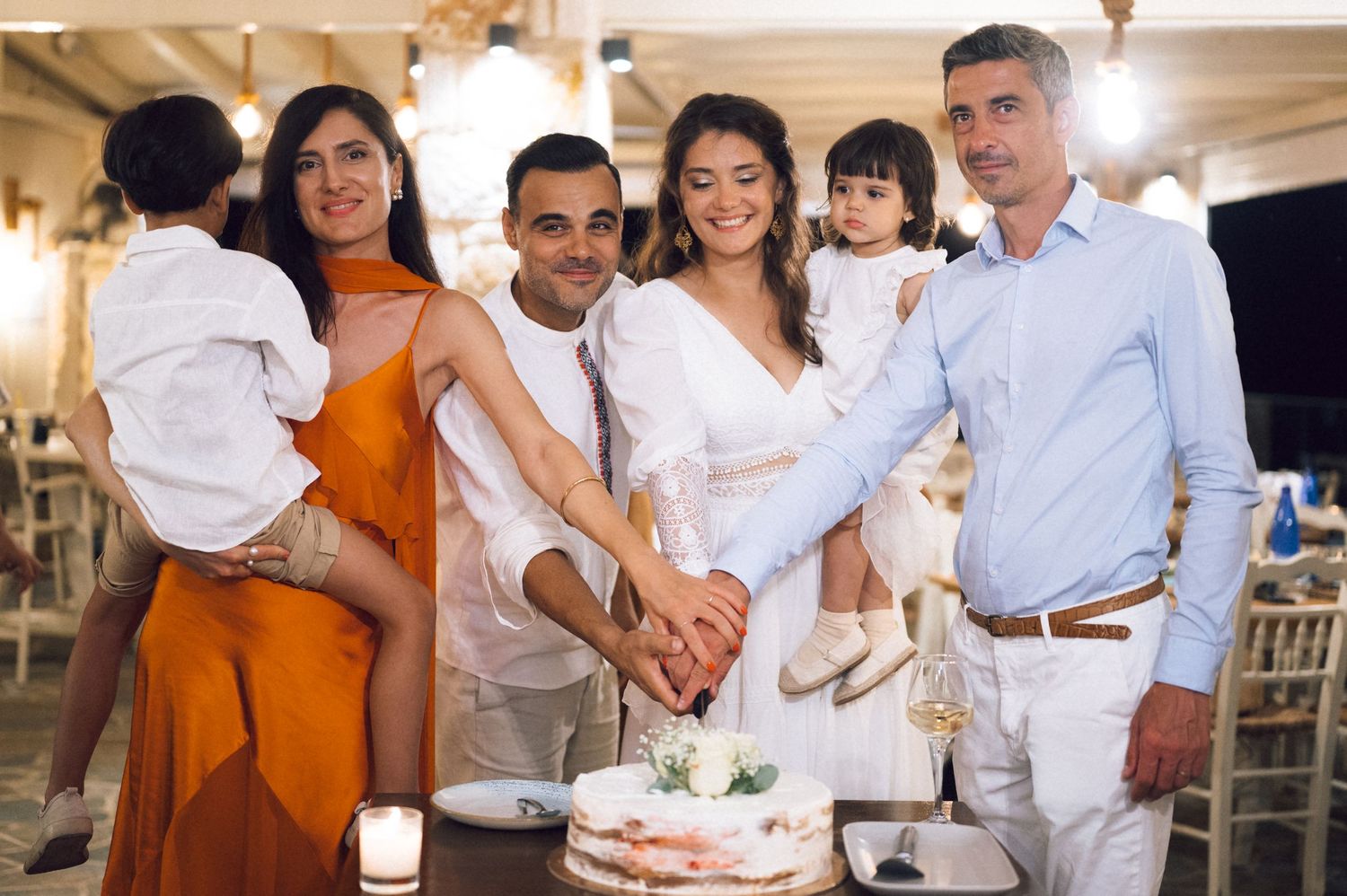 Family gathering around a wedding cake cutting ceremony at an elegant indoor reception venue.