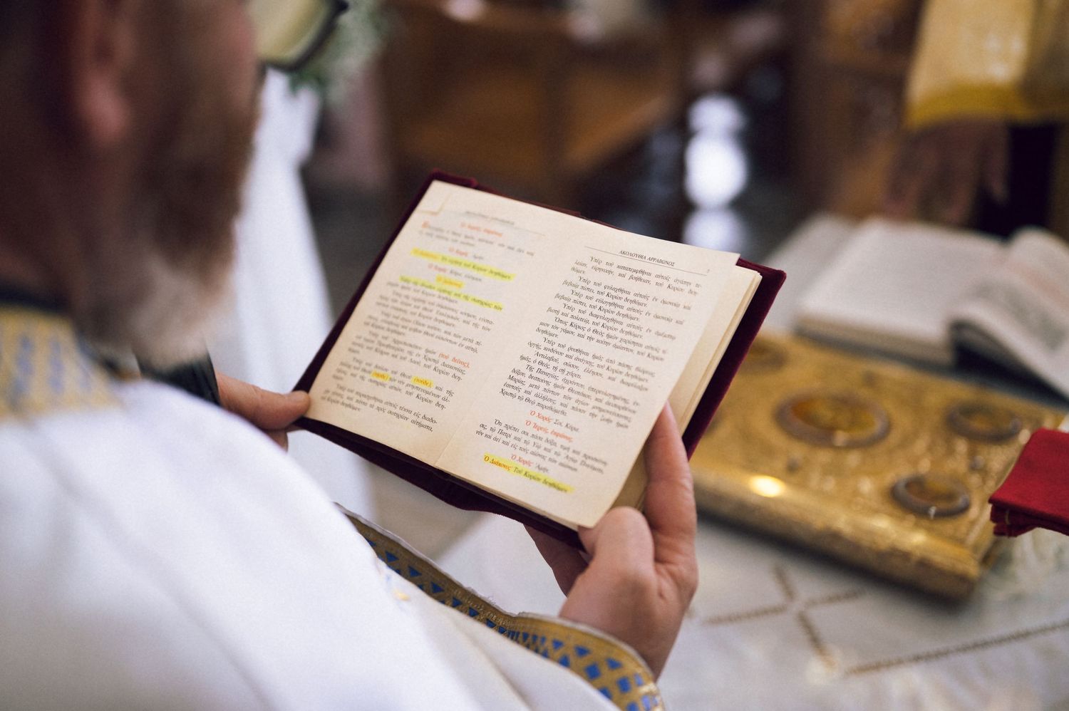 Priest reading highlighted text in a religious book during a church ceremony.