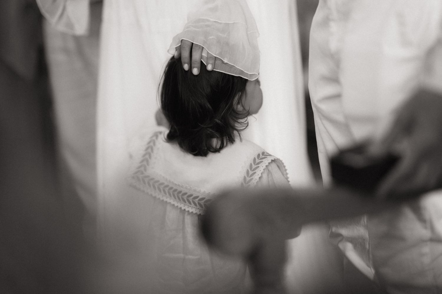 Black and white photo of a bride having her veil adjusted during wedding preparations.