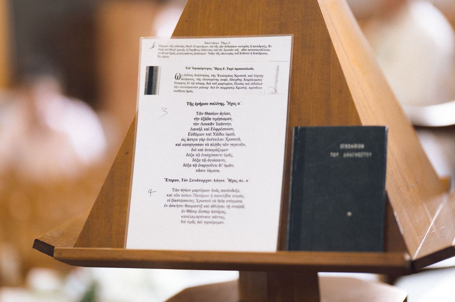 Wooden church lectern holding an open hymnal and a black Bible during a religious ceremony.