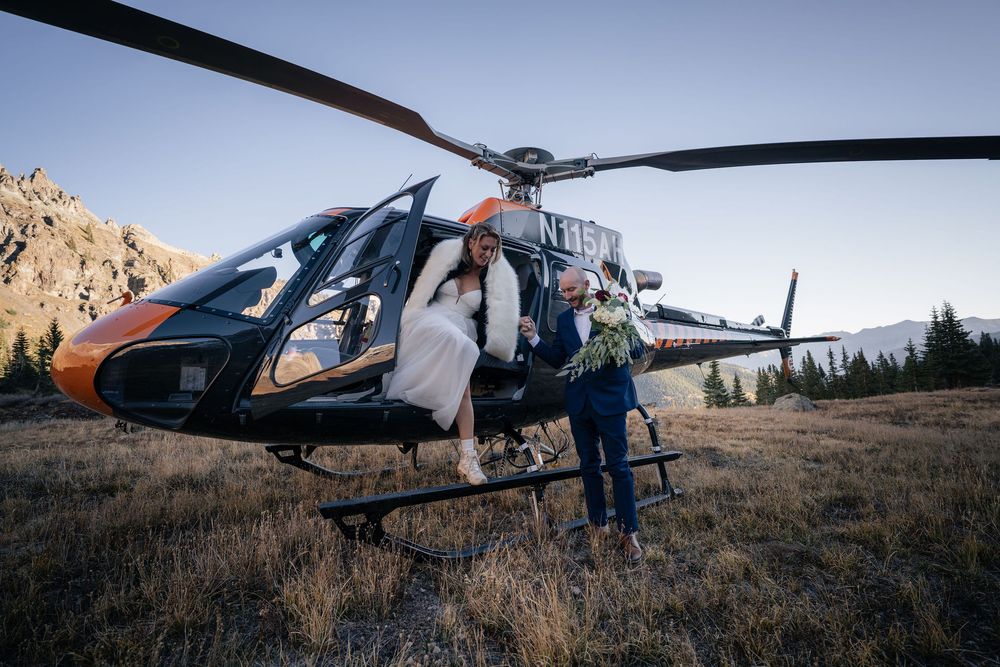 Bride and groom holding hands as they exit a helicopter after their wedding in Telluride, CO