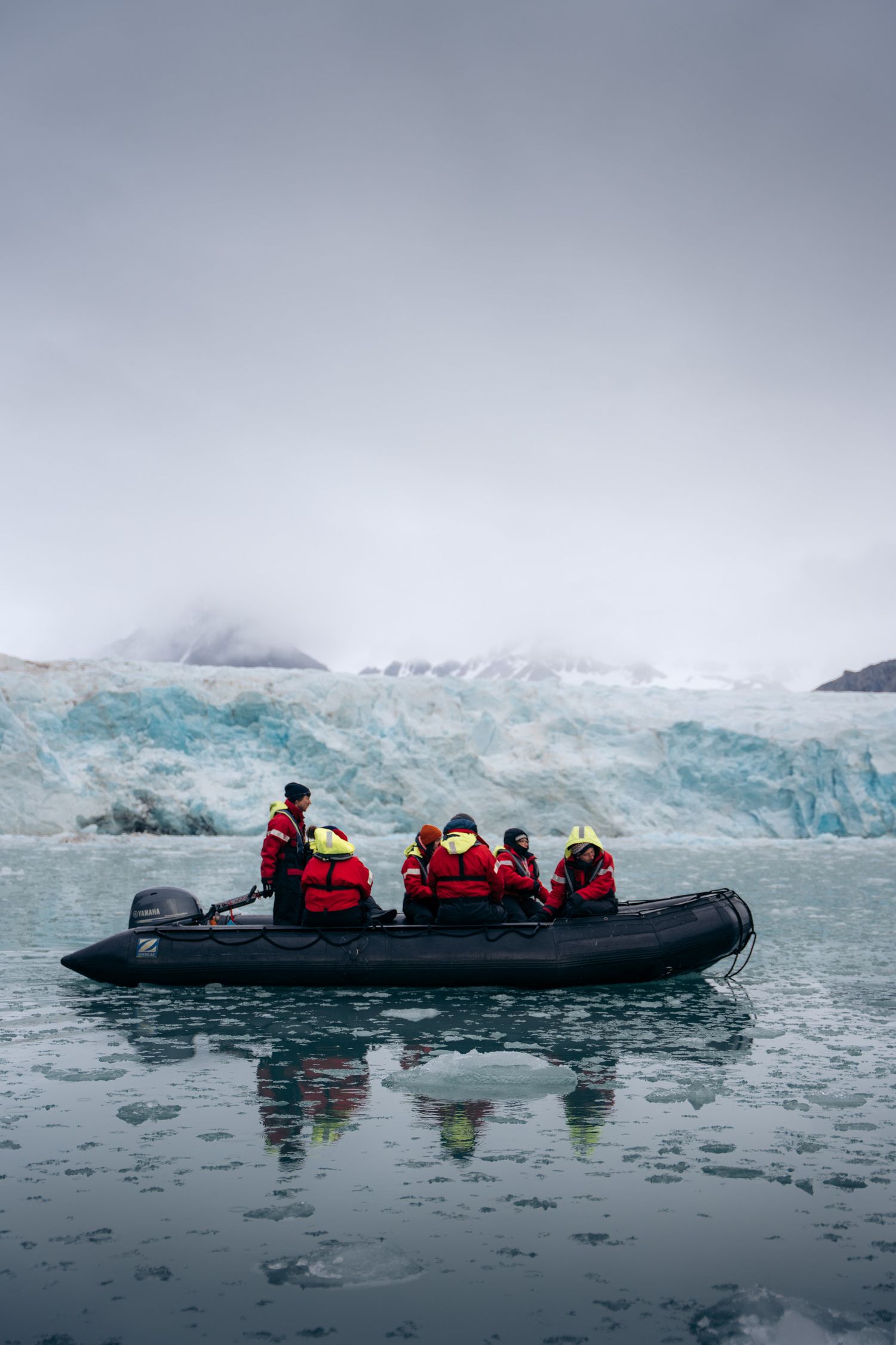Zodiac de passagers longeant de profil une muraille de glace bleutée