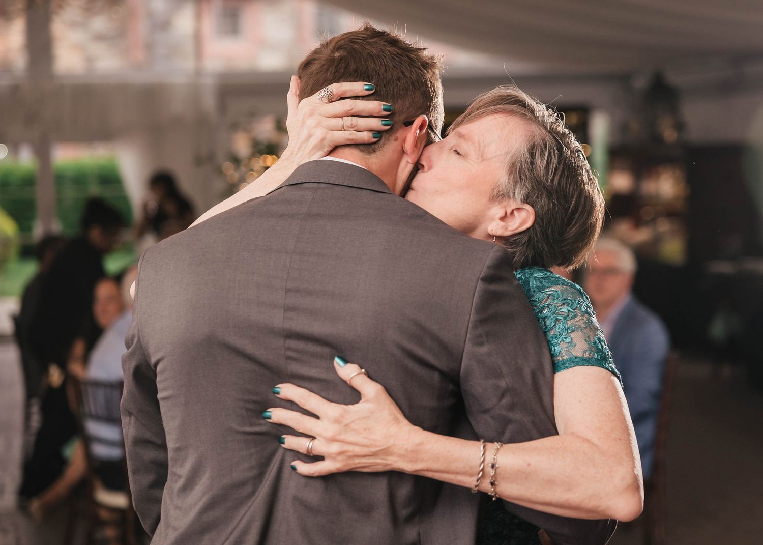 Groom's mother kissing his cheek during their dance, her hand cradling the back of his head.