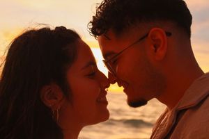 Close-up of a couple sharing an intimate moment at sunset with warm golden light on their faces.