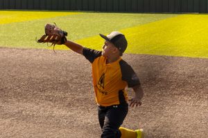 Youth baseball player reaching with his glove to make a catch during a game in Oklahoma.