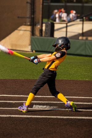 Youth baseball player making contact with the ball during an at-bat in Oklahoma.