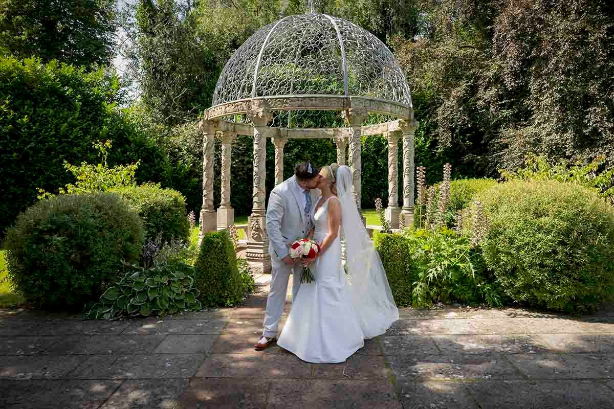 Bride and Groom share a kiss in front of the gazebo at Dalston Hall- wedding venue- Carlisle