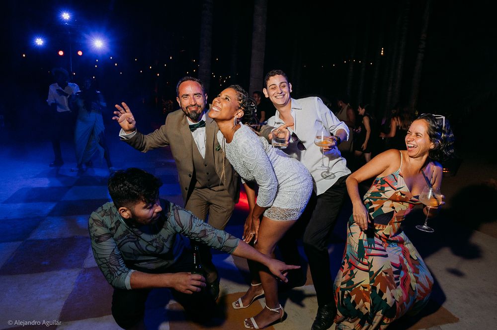 Group of friends dancing and posing together at an outdoor evening party celebration.