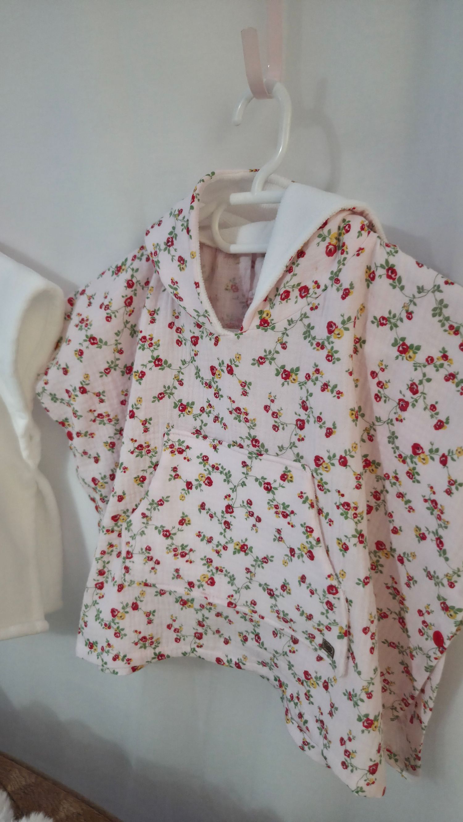 Pink floral short-sleeve children's blouse with collar hanging on a white hanger.
