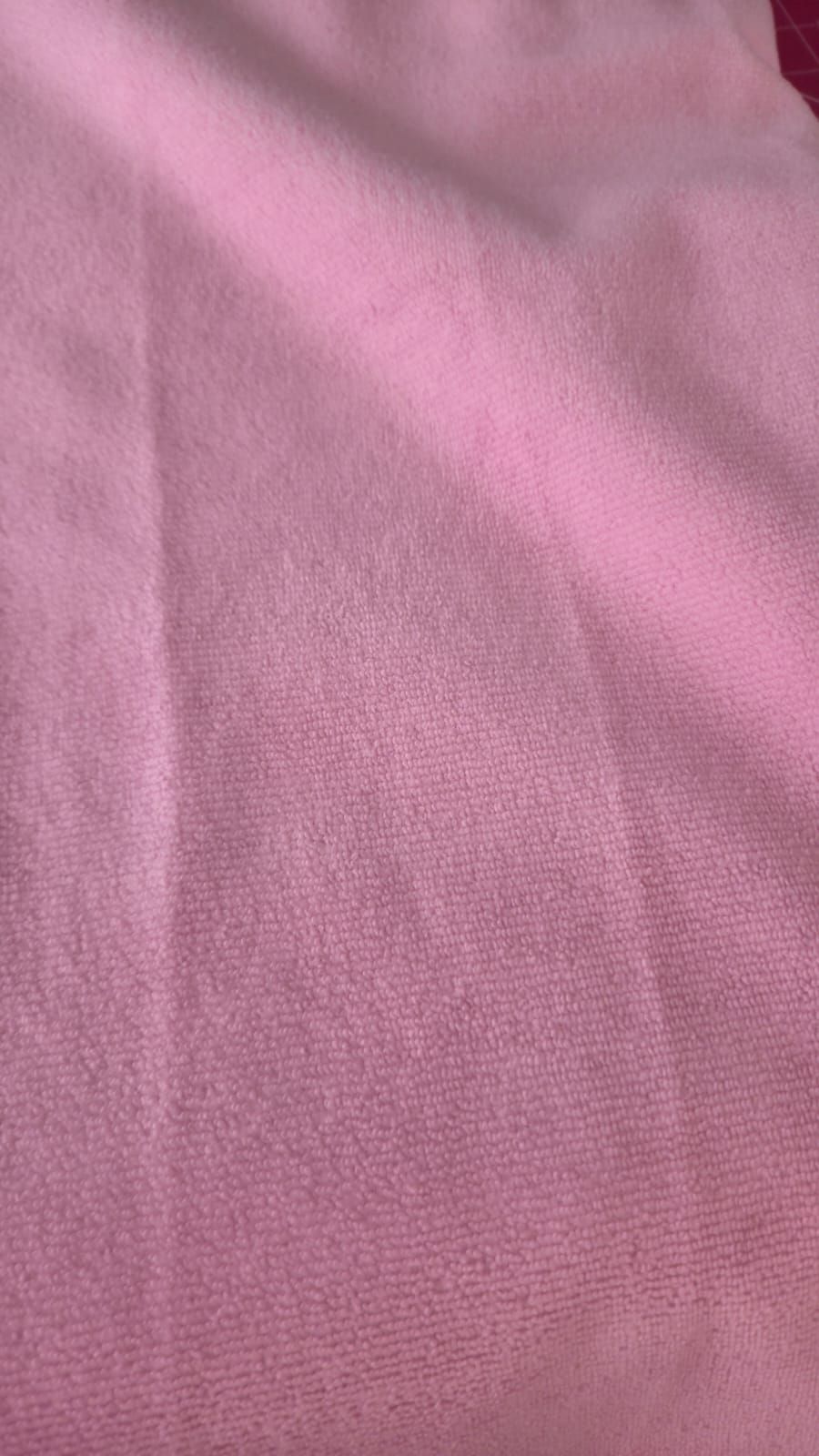 Close-up of soft pink fabric textile with a smooth woven texture and subtle folds.