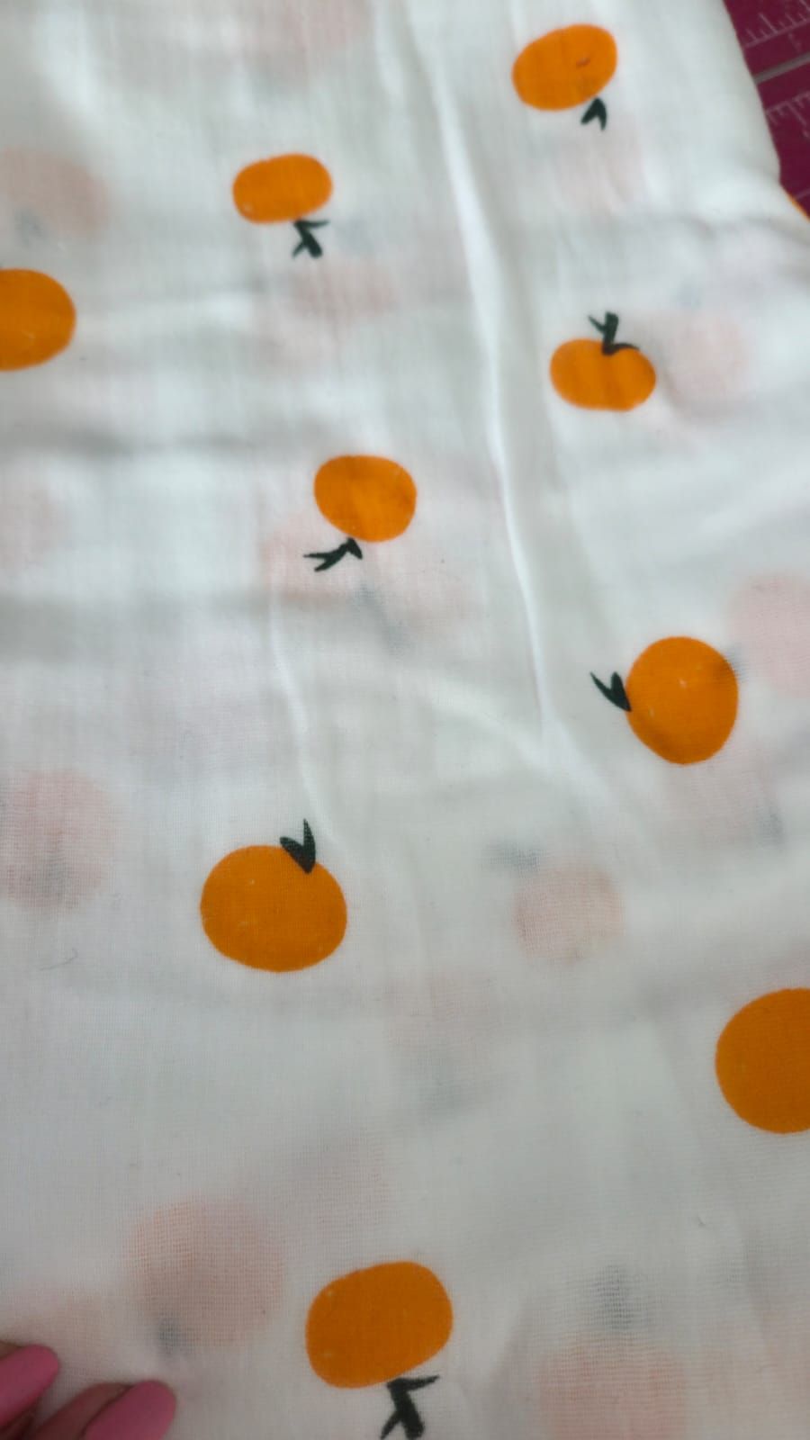 White muslin fabric featuring a scattered pattern of bright orange tangerines with green stems on a light background.