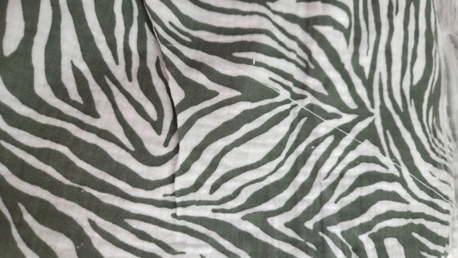 Close-up of zebra print fabric featuring bold black and white stripes on a soft textile material.