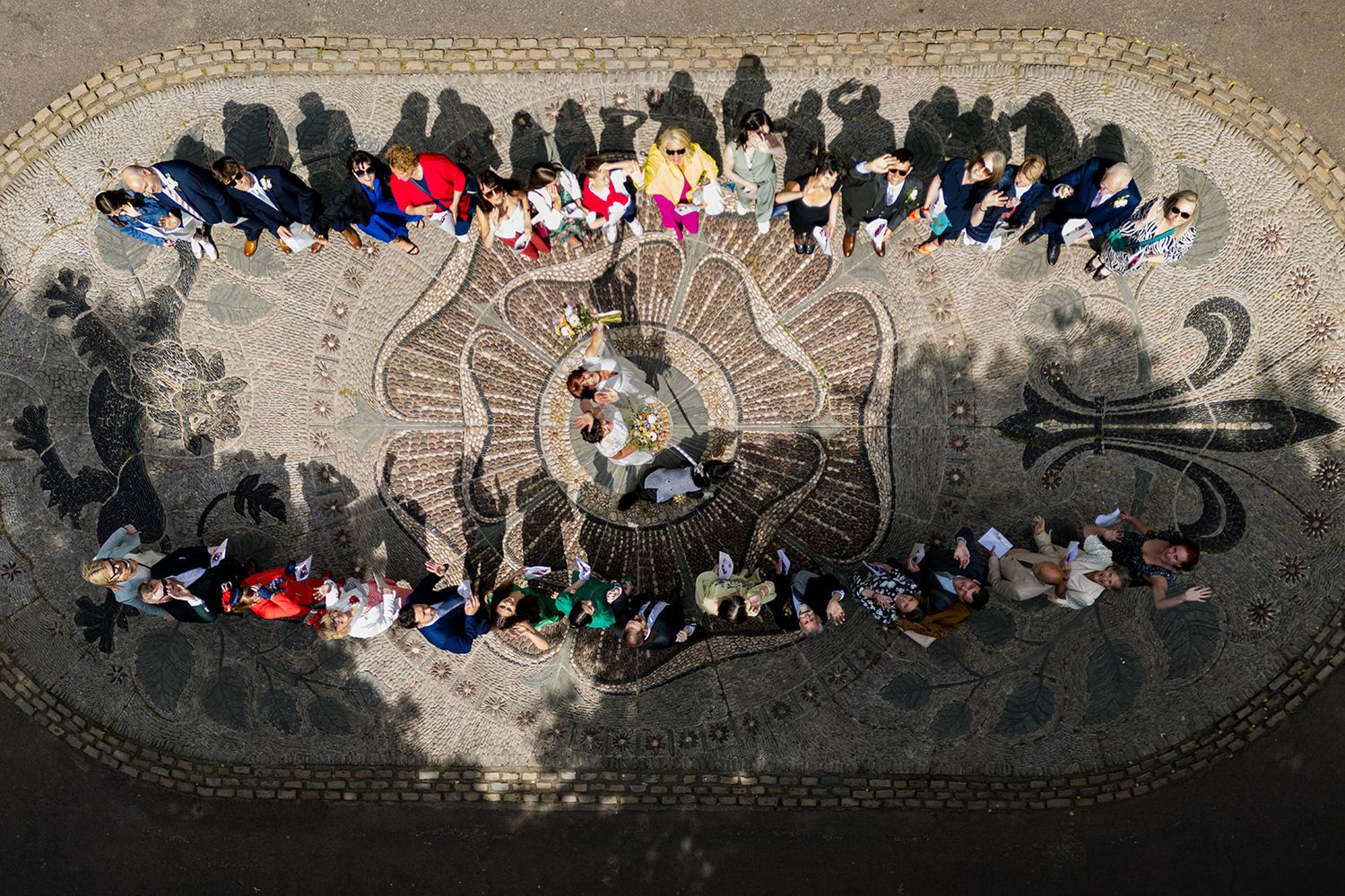 Aerial view of a large group of people gathered around an ornate mosaic pavement in a circular pattern.