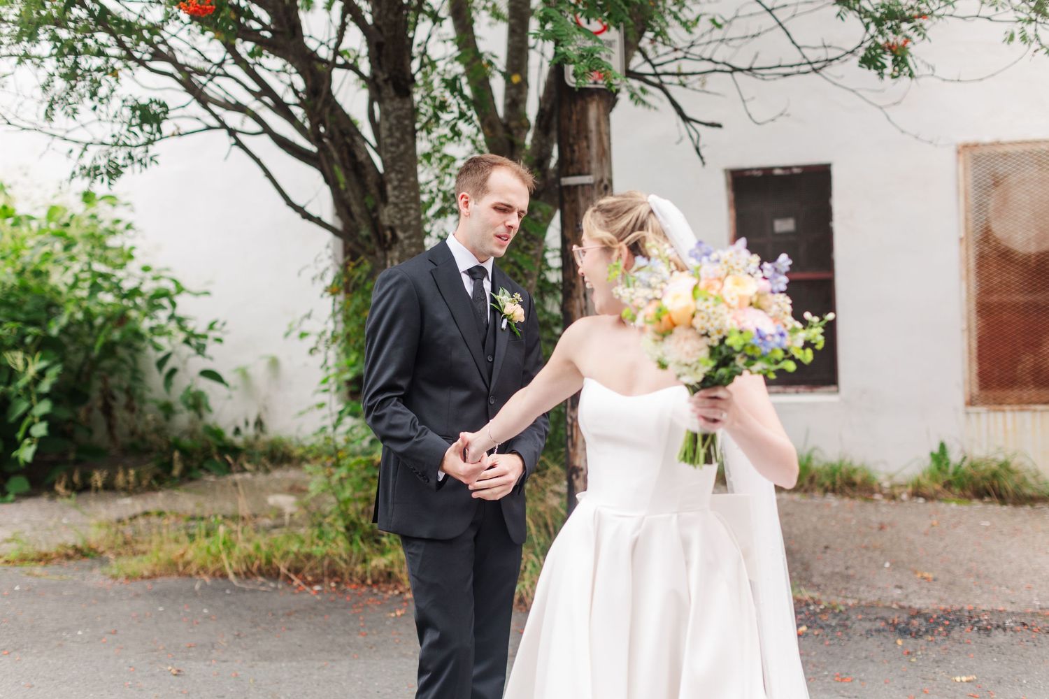 Bride and groom share a tender moment outdoors, with bride holding a colorful bouquet during their wedding day.