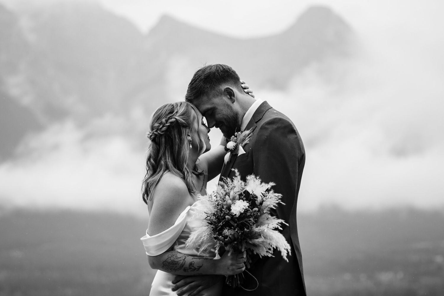 Black and white portrait of bride and groom forehead to forehead with dried bouquet, Canmore wedding photographer