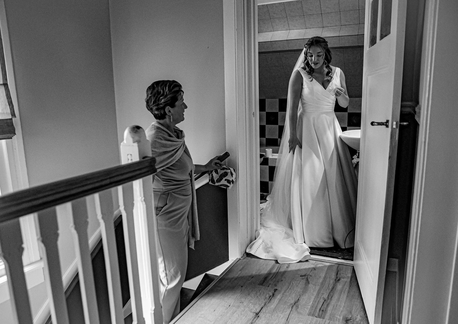 Bride and groom pose together in a rustic barn with hay bales and a goat, bride wearing a long white veil.