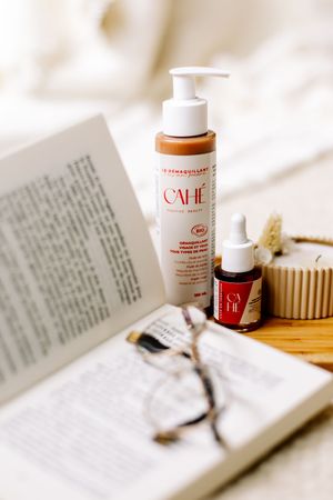 Produits de soin Cahé Cosmetics disposés près d'un livre ouvert avec une paire de lunettes