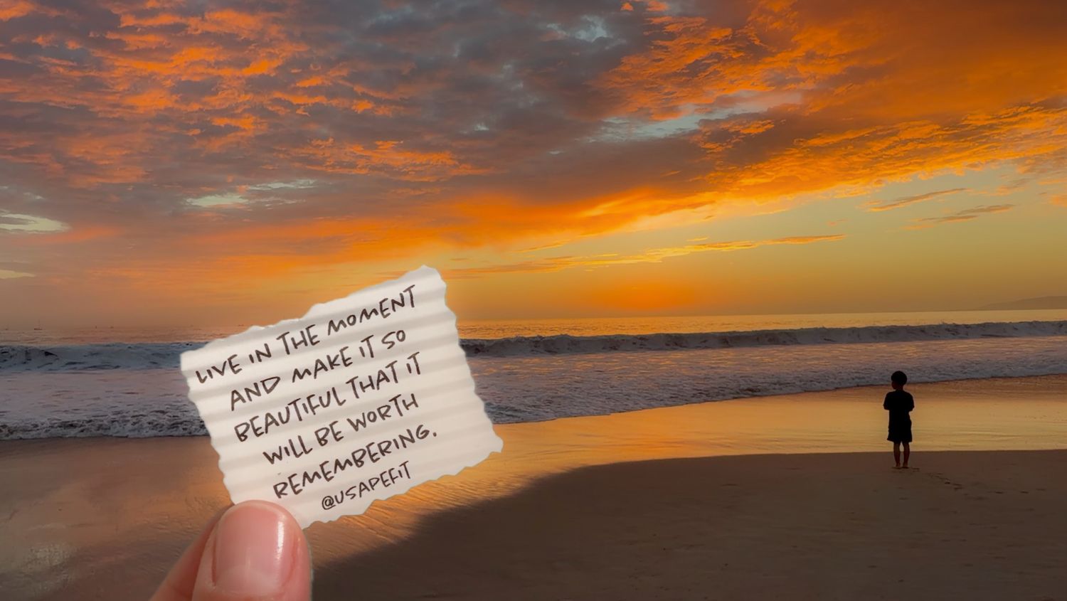 Hand holding a handwritten inspirational quote note against a vivid orange sunset beach with a lone person standing near the waves.