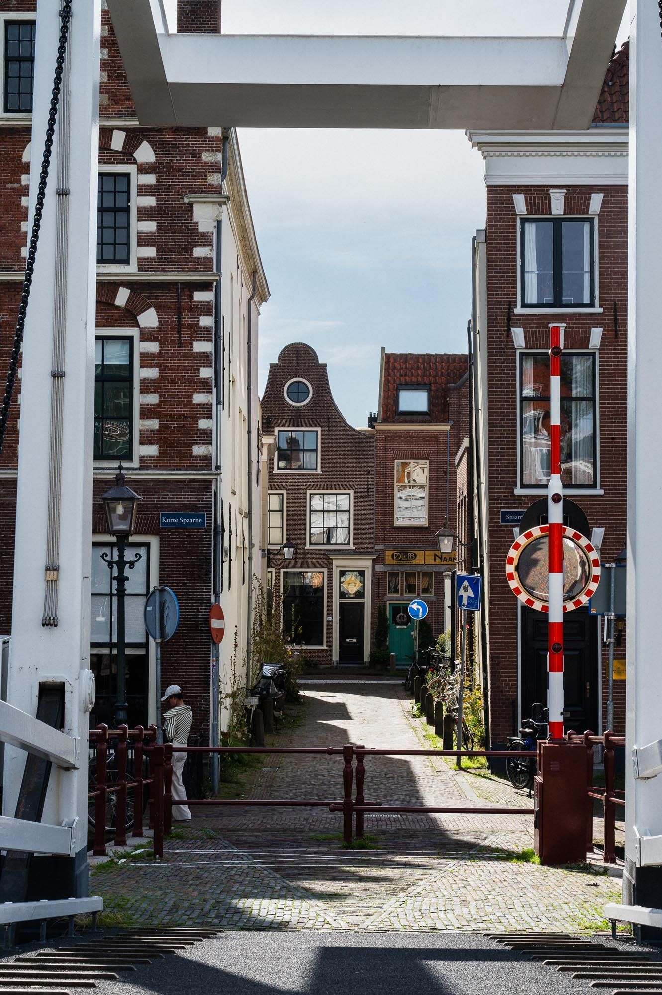 Narrow cobblestone street lined with traditional Dutch brick buildings and a drawbridge in a historic Netherlands town.