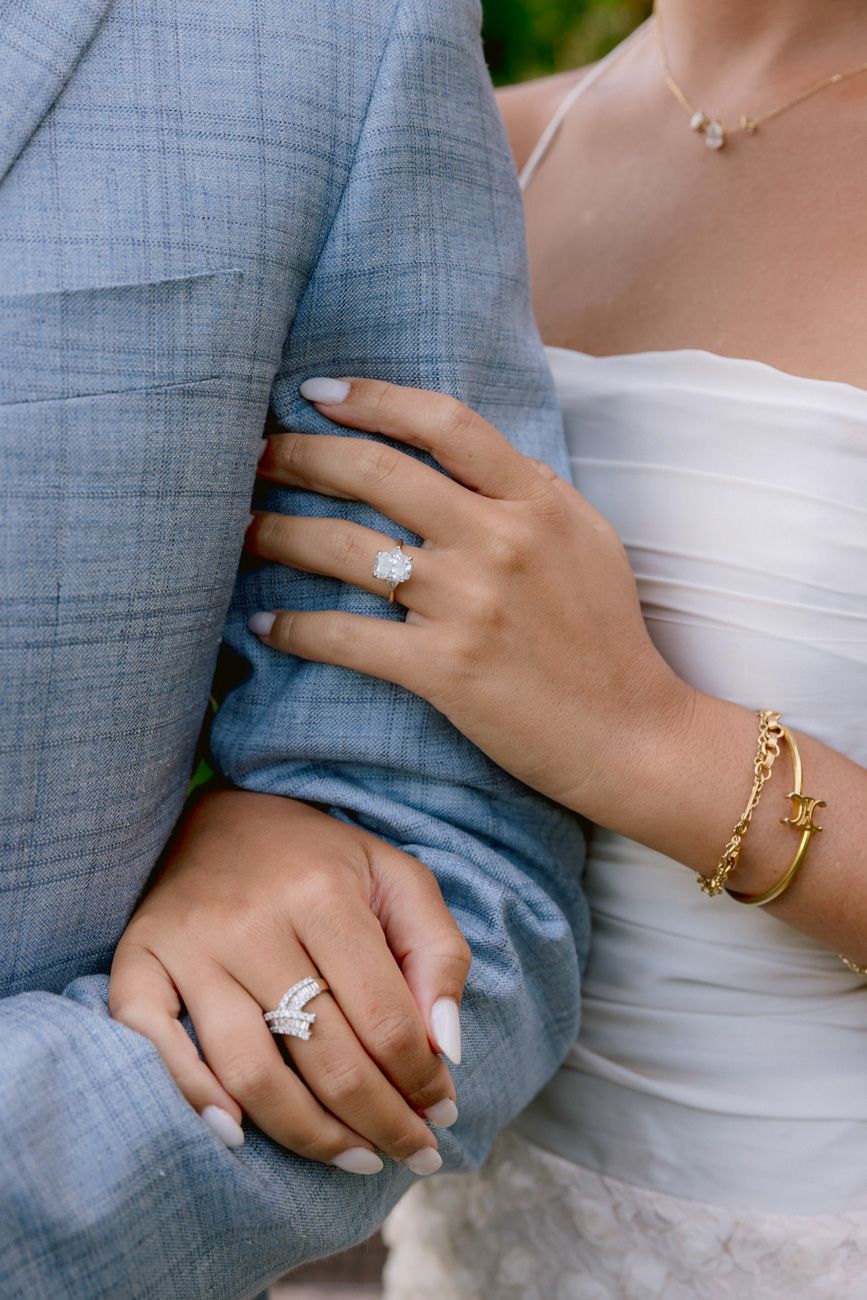 Close-up of the bride and groom embracing, highlighting her sparkling engagement ring and fine jewelry
