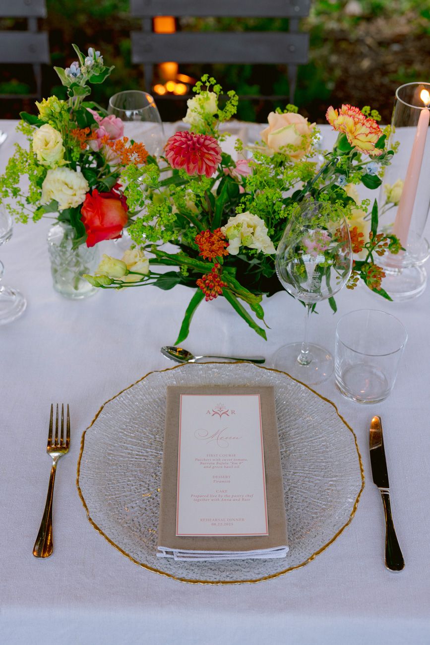 Vibrant colourful floral centerpiece and a personalized menu decorating a rehearsal dinner table in a Lake Garda vineyard
