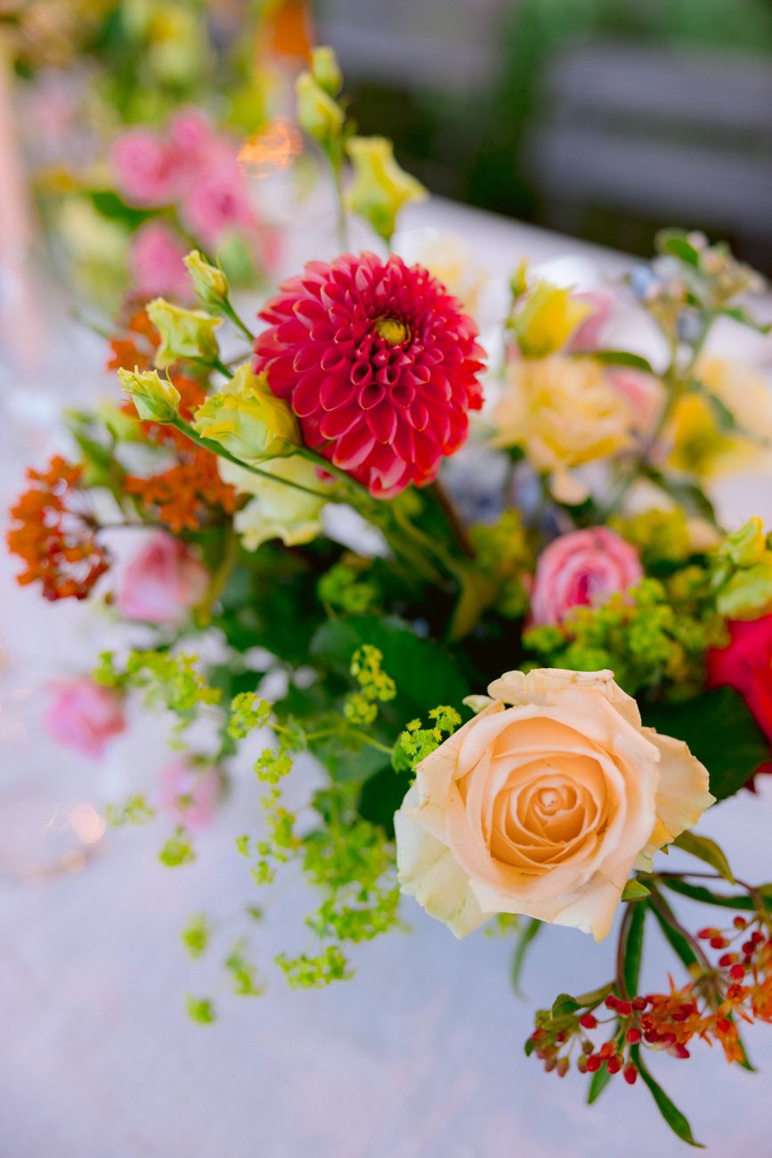Vibrant colourful floral centerpiece decorating a rehearsal dinner table in a Lake Garda vineyard