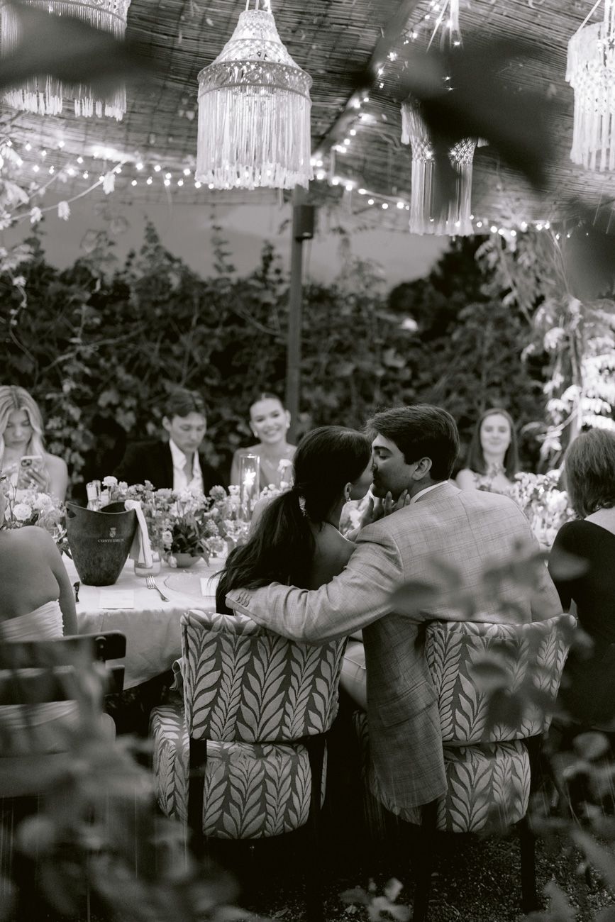 Bride and groom sharing a romantic kiss at their vineyard rehearsal dinner table near Lake Garda