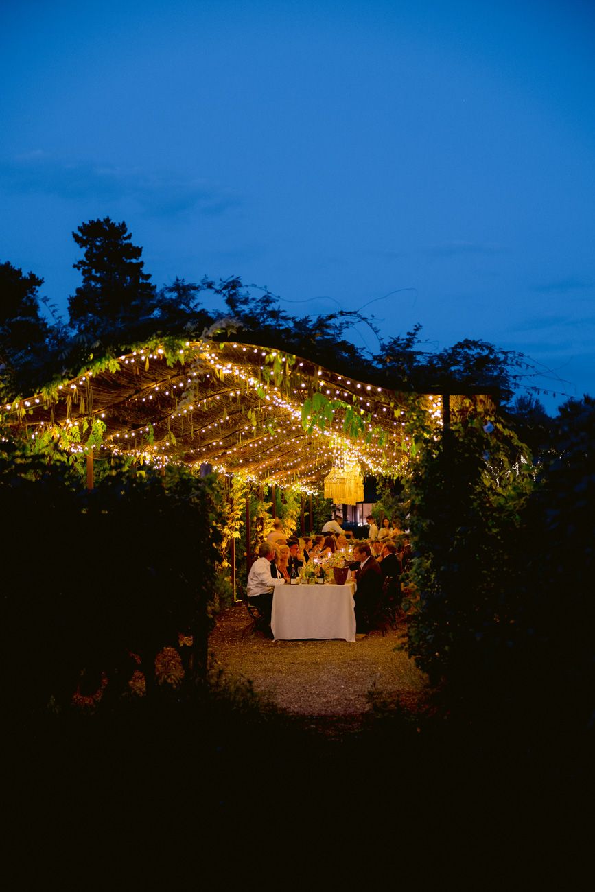 Vineyard aisle brightly illuminated with fairy lights for an evening rehearsal dinner near Lake Garda