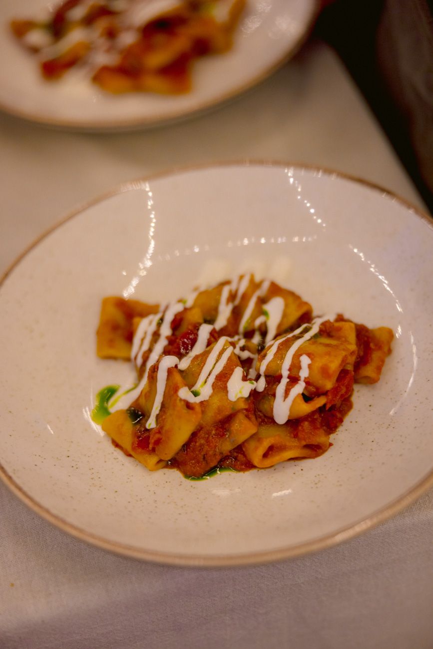 Plated paccheri pasta with tomato sauce and creamy burrata served at a Lake Garda rehearsal dinner