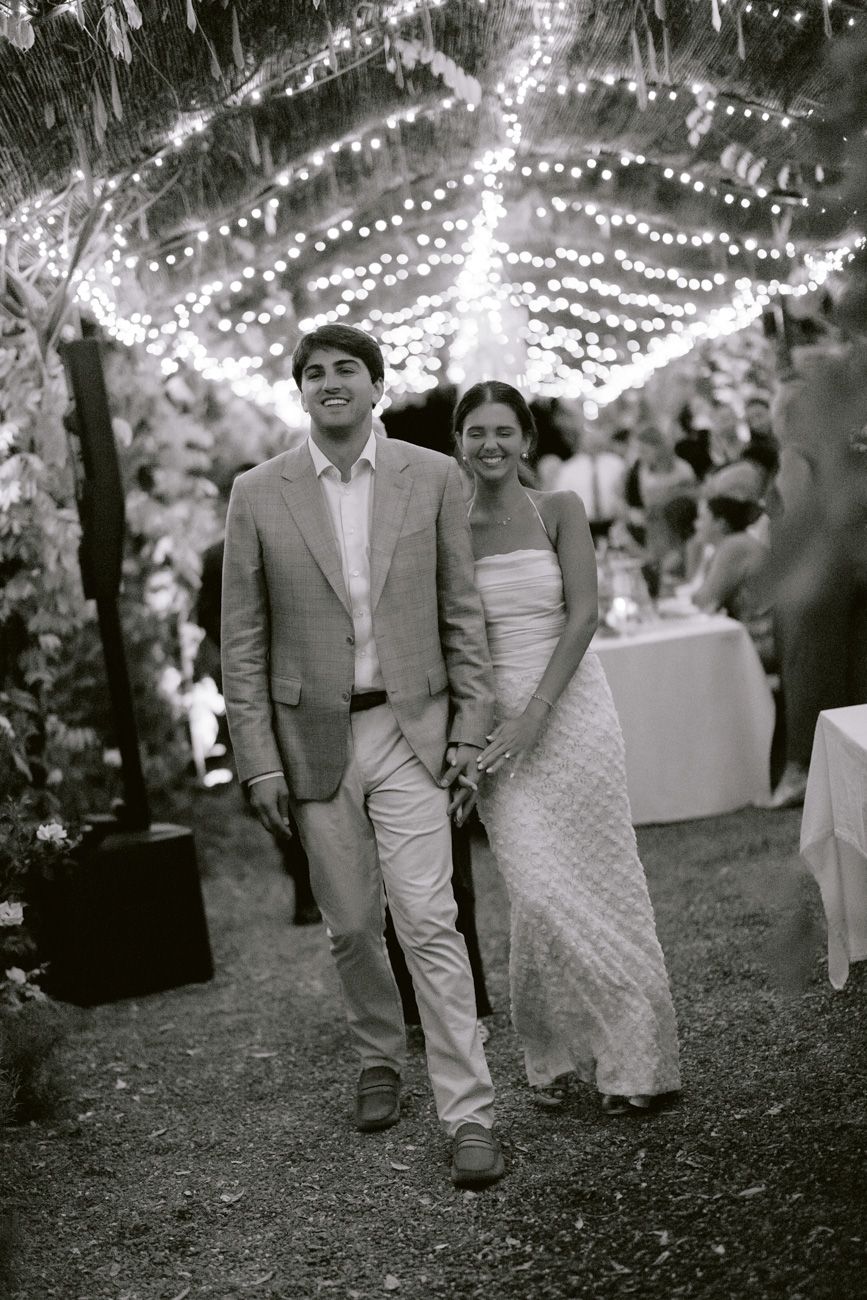 Newlyweds embracing under a canopy of fairy lights in a romantic Lake Garda vineyard setting