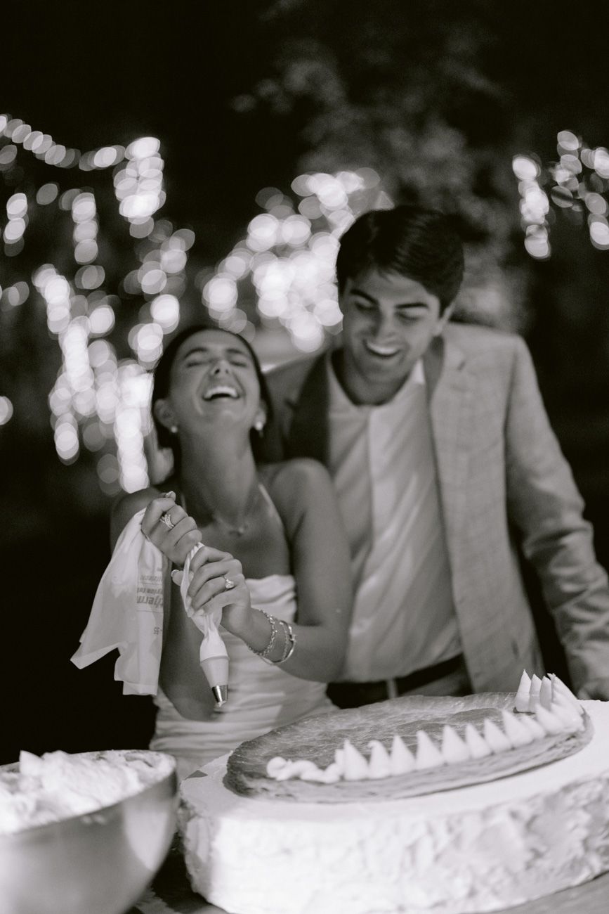 Bride and groom assembling a millefoglie cake during an outdoor rehearsal dinner near Lake Garda