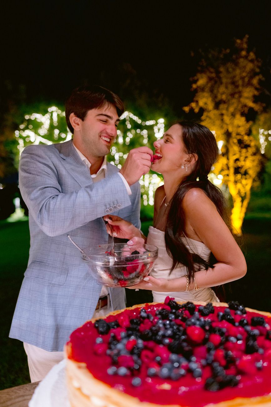 Bride and groom eating their cake during an outdoor rehearsal dinner near Lake Garda