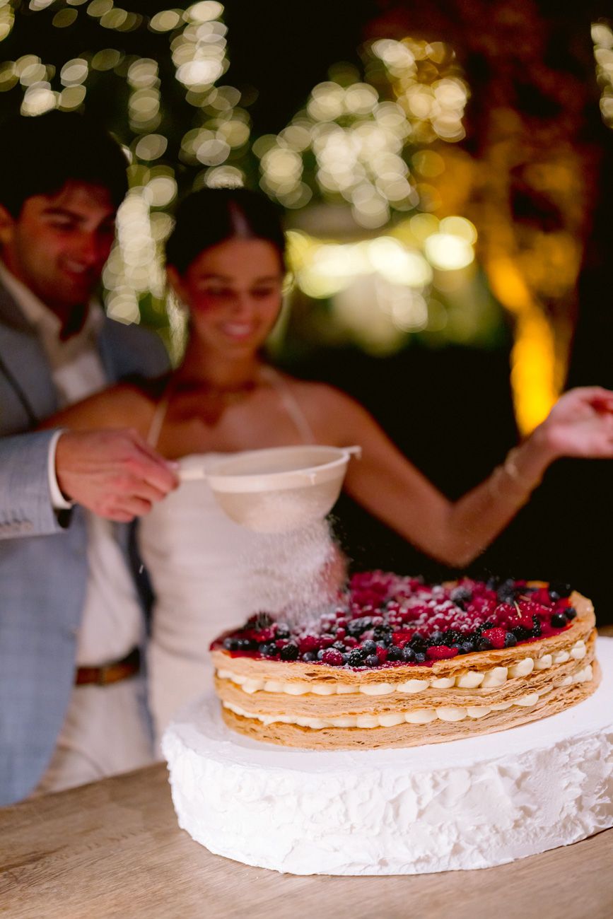 Bride and groom assembling a millefoglie cake during an outdoor rehearsal dinner near Lake Garda