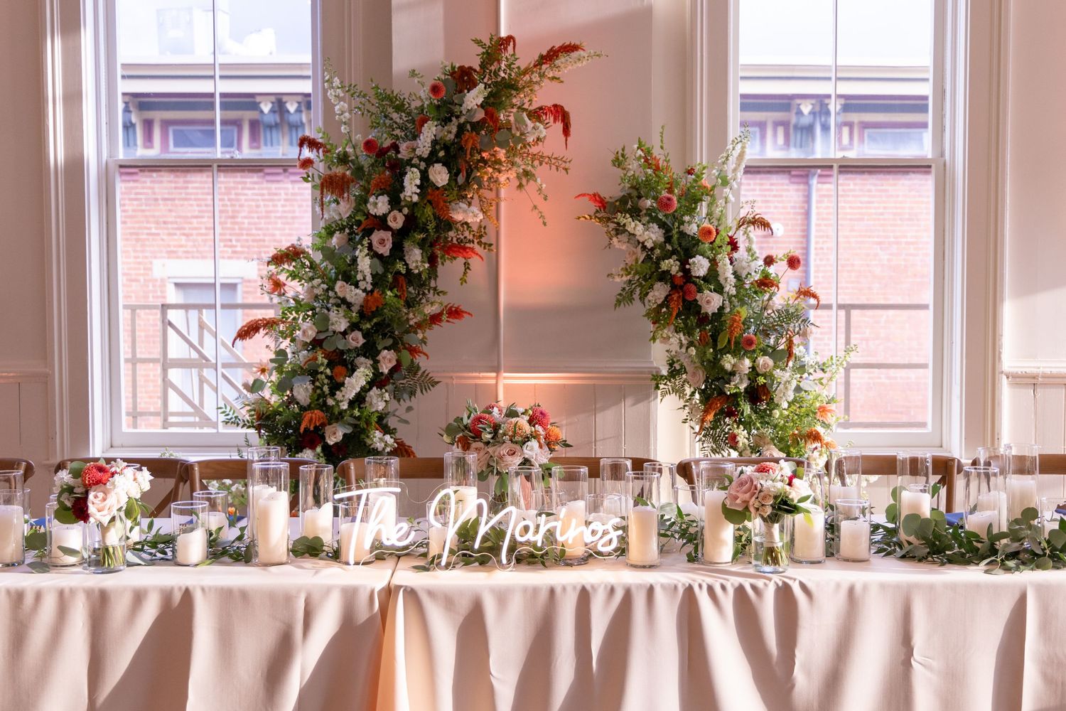Elegant wedding head table with floral arches and candles at The Alcove Cincinnati wedding event space.