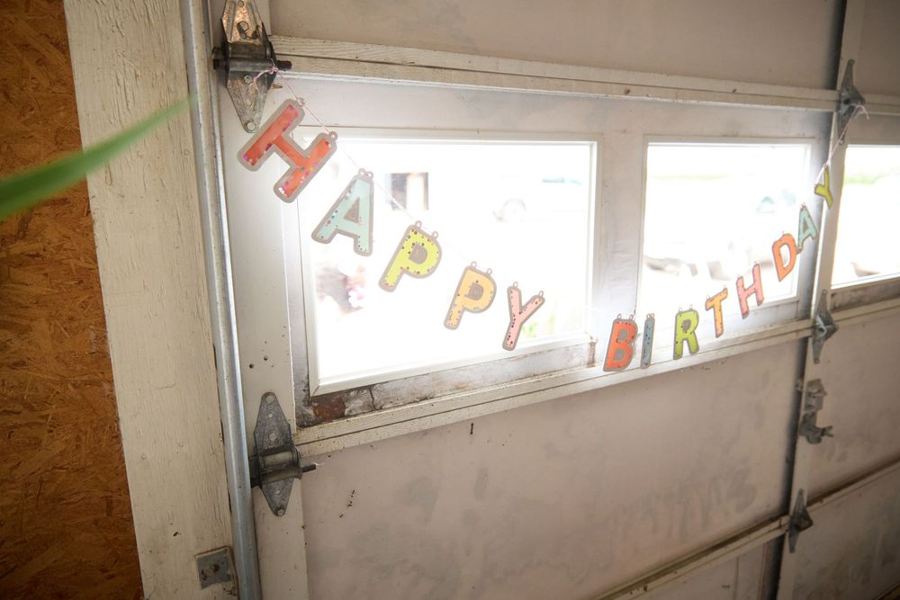 Colorful Happy Birthday banner displayed in a garage door window, celebrating a special occasion.