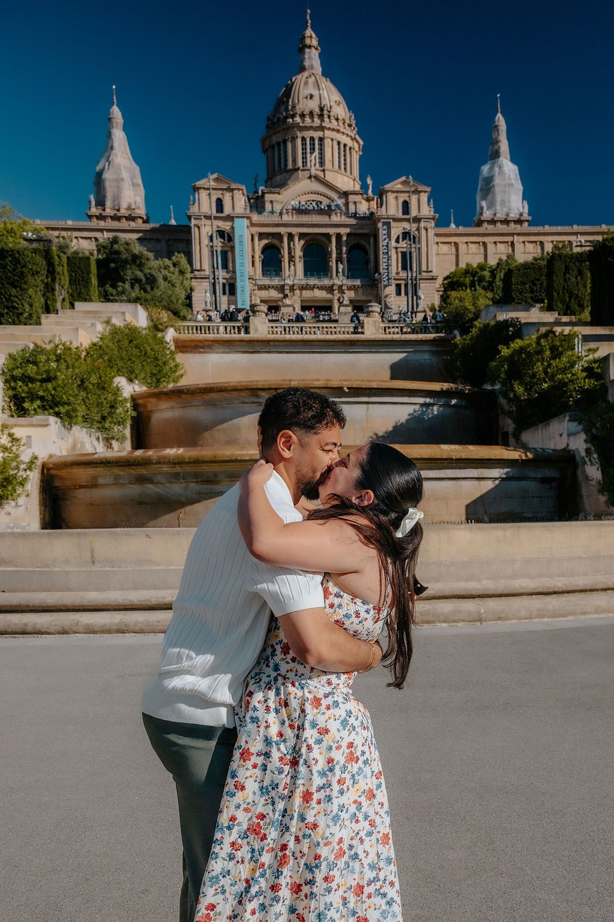 Romantic couple framed against a grand wall of water next to the Sileno Bailando statue in Montjuic.