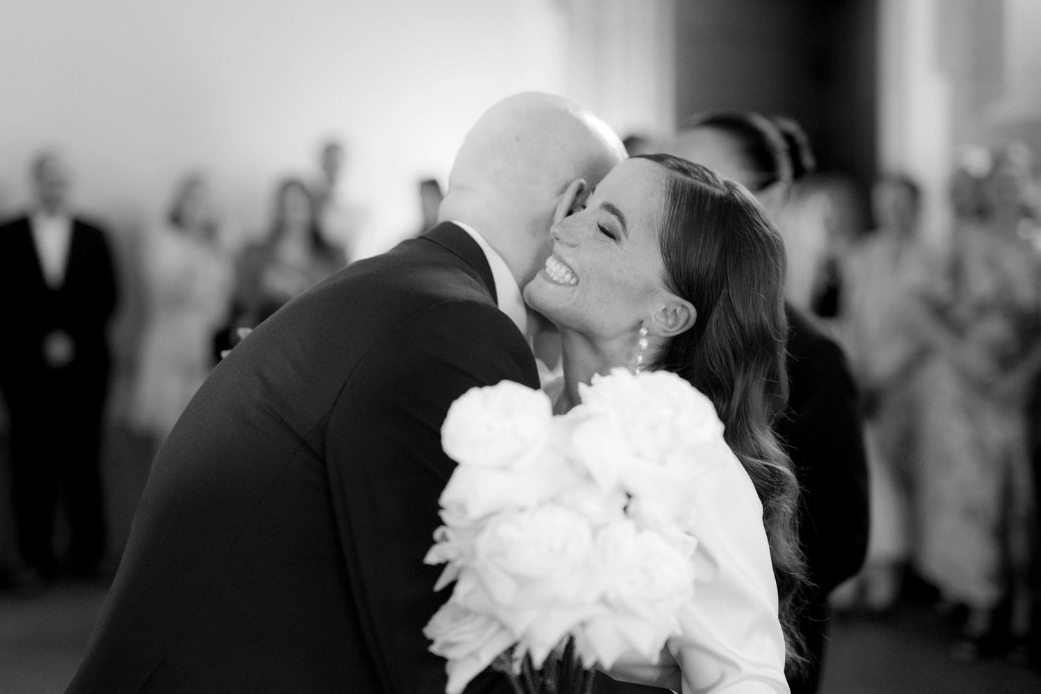 Black and white photo of a bride and groom sharing a tender embrace during their first dance at a wedding.