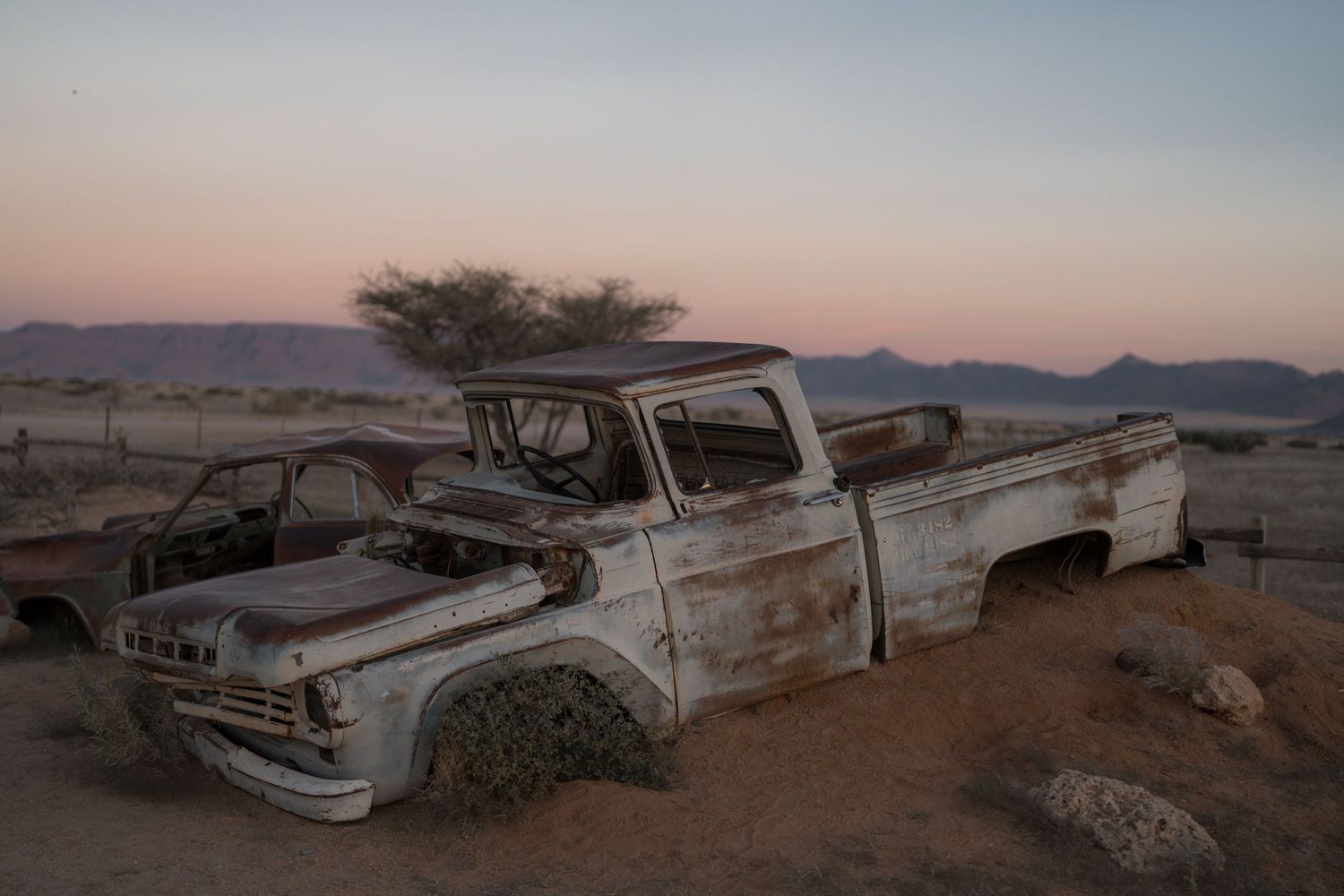 vieille carcasse de voiture à moitié ensevelie dans le sable avec le désert du namib en arrière-plan