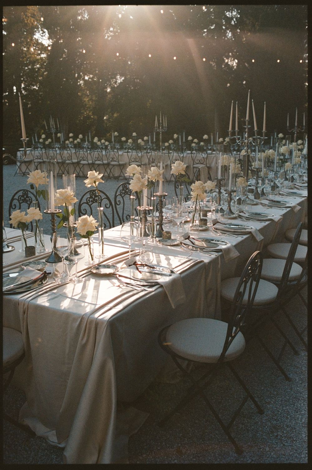 Elegant outdoor wedding reception table set with white flowers, candelabras, and silver decor.