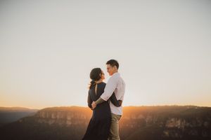 Couple embracing at golden hour on a mountain overlook with stunning valley views.