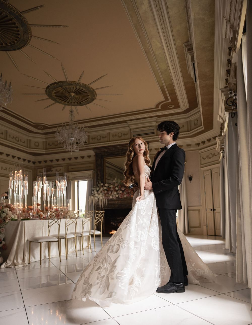 Bride in a strapless floral patterned wedding dress and groom in a black tuxedo pose in the grand ballroom at The Kentucky Castle.