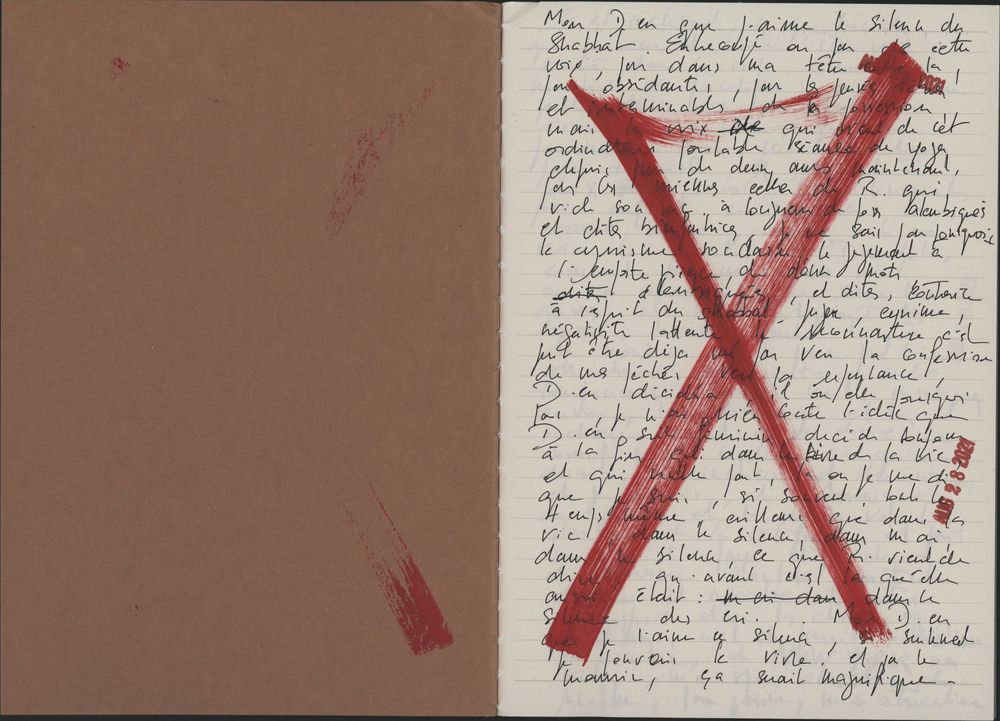 Handwritten letter with bold red X mark overlaid on cursive text, beside a brown cardboard cover.