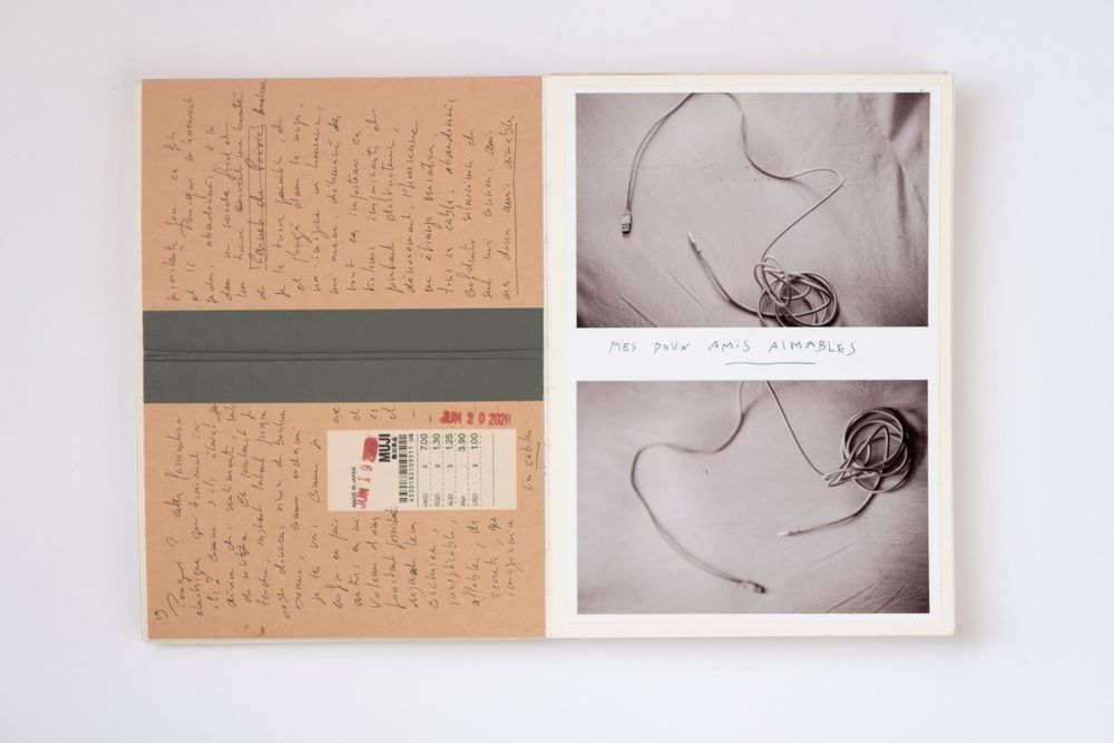 Open journal with handwritten notes, vintage ticket, and two black-and-white photos of tangled string on white background.