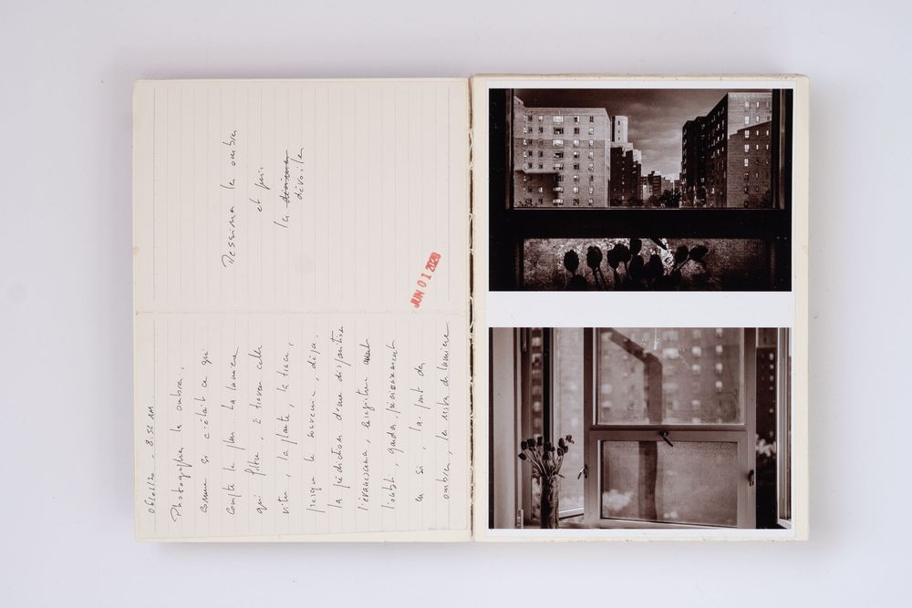 Open book with handwritten notes on left page and two vintage black-and-white urban photography prints on right page.
