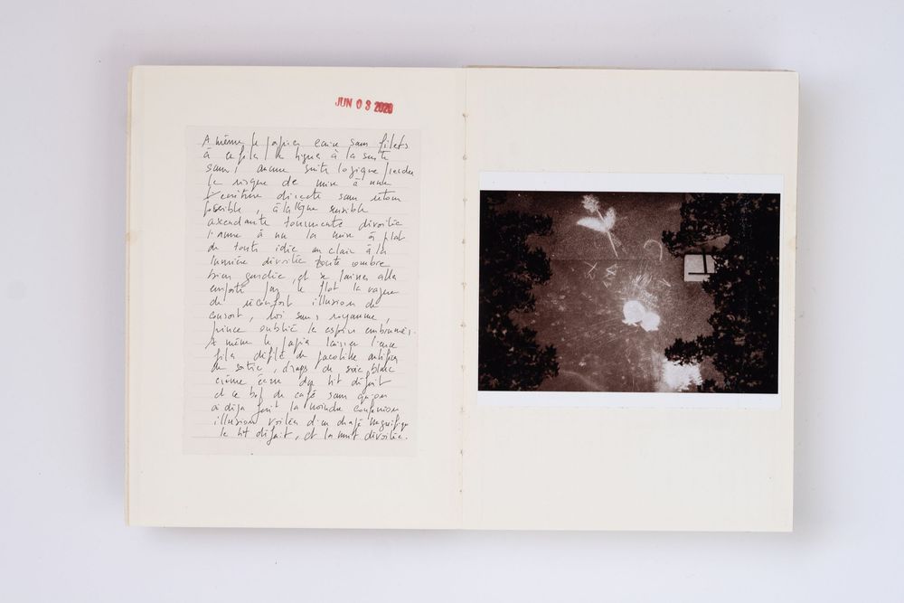 Open book with handwritten journal notes on left page and a dark photograph on the right page.